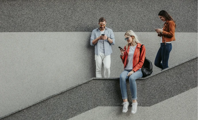 Basamaklı oturma alanında akıllı telefonlarını kullanan üç kişi